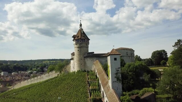 Aerial dolly in of Munot circular fortress and tower on a verdant hill revealing picturesque Schaffhausen village, Switzerland