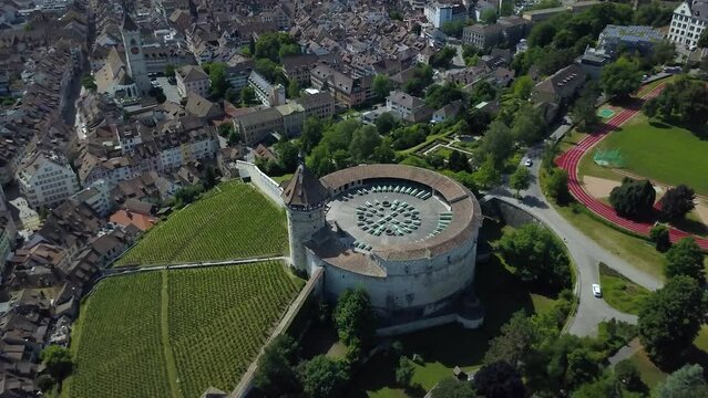 Aerial orbit of Munot circular fortification in verdant hill next to High Rhine river and Schaffhausen village between woods, Switzerland