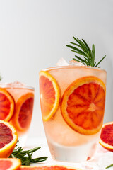 Fruity refreshing drink with blood oranges and ice and rosemary, delicious sweet juice
