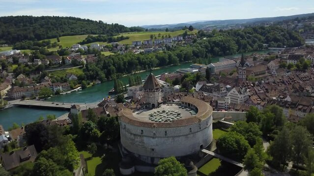 Aerial orbit of Munot circular fort on a hill near High Rhine river with bridges and village surrounded by woods, Schaffhausen, Switzerland