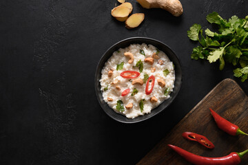 Indian Curd Rice with pomegranate, cilantro, mustard seeds, ginger on black background. View from above. Copy space.