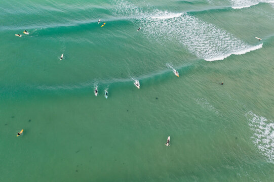 Aerial view of a group of surfers catching a wave in the ocean