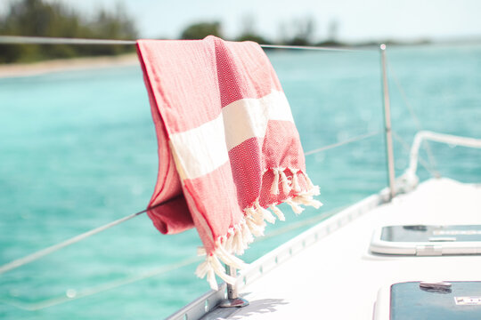 Red turkish towel hanging on wire railing of boat on the water