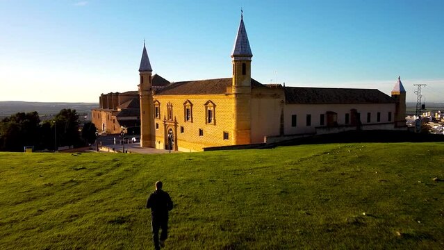 Aerial dolly in of a person jogging and the facade of the university of osuna, seville in the background