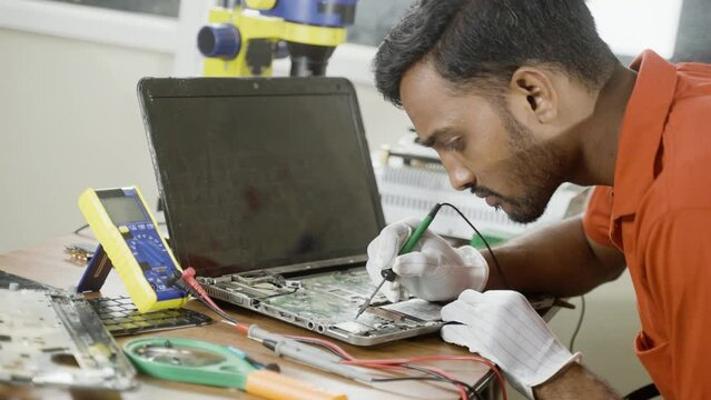concentrated technician busy reparing laptop at workshop - concept of professional worker, skill jobs and repair service.