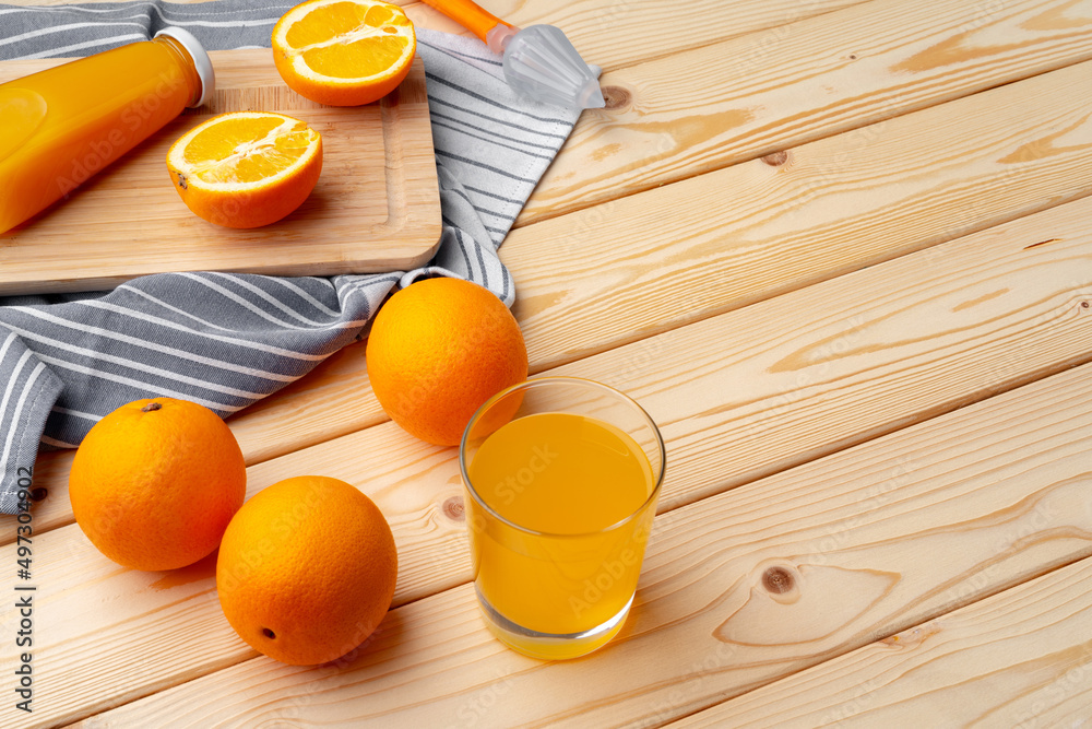 Wall mural Fresh orange juice in the glass with orange fruit on wooden background