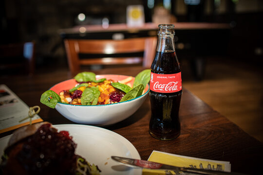 Coca Cola bottle in a typical American restaurant with burgers and salad on a table