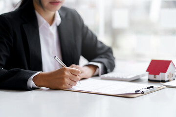 Real estate agent and customer make contract to buy and sell house and land. Approval of a contract to buy or sell a home. Offers mortgage loans and home insurance concept.