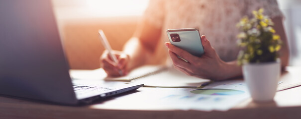 Woman writing in notebook and reading messages.