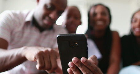 Black family looking at smartphone together at home
