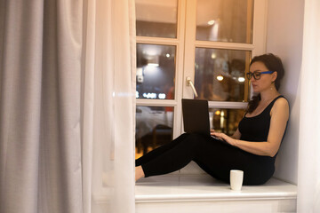 Mature woman sitting with computer in her home, browsing, writing, researching with colleagues. Concept of communication and working from home