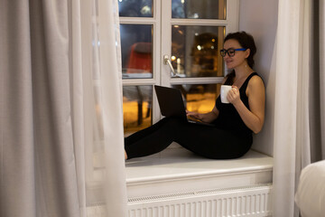 Mature woman sitting with computer in her home, browsing, writing, researching with colleagues. Concept of communication and working from home