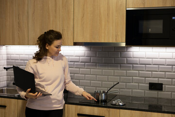 Mature woman cooks at home looking at new recipe on the internet. Learn new recipes from home...