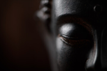 Meditating Buddha Statue on dark background. Soft focus. Close up. Copy space. 