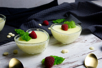 Pudding dessert with raspberry and mint on wooden floor. Near the teaspoon.