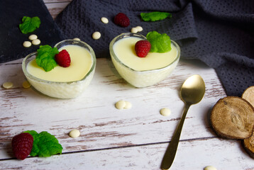 Pudding dessert with raspberry and mint on wooden floor. Near the teaspoon.