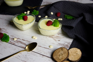 Pudding dessert with raspberry and mint on wooden floor. Near the teaspoon.