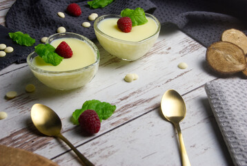 Pudding dessert with raspberry and mint on wooden floor. Near the teaspoon.