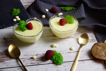 Pudding dessert with raspberry and mint on wooden floor. Near the teaspoon.