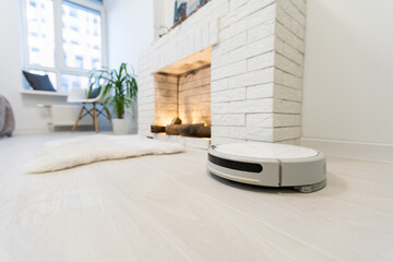 Smart House. Vacuum cleaner robot runs on wood floor in a living room