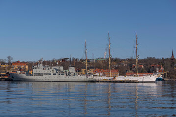 Fototapeta na wymiar Wharf island with various sips as old military and sailing boats a sunny spring day in Stockholm 