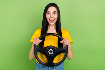 Portrait of excited funky person arms hold wheel stare speechless camera isolated on green color...
