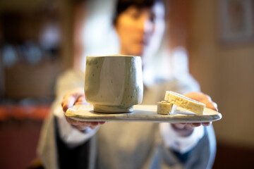 Female Artist giving to camera Simple breakfast in unique ceramic pottery  at her home