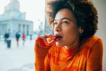 Contemplative pensive young black woman eating strawberry