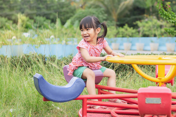 Portrait image of 4-5 years old childhood. Happy Asian child girl playing with the slider bar toy at the playground. Kid and sport. Exercise for health.