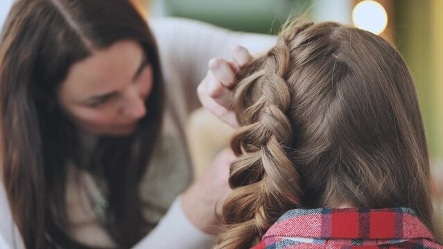 The girl makeup artist makes a braid for the model.