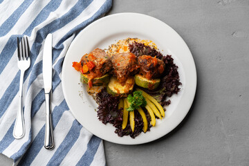 Cooked meat with fresh vegetable salad on a white plate
