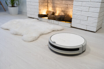 Obraz na płótnie Canvas robotic vacuum cleaner on laminate wood floor smart cleaning technology