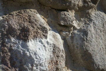 An efflorescence effect sample - salt deposits on stone masonry. A close-up view of a boulder wall in a historical building. The castle ruins stone construction fragments in macro with salt sediments.