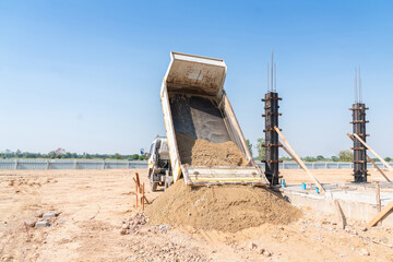 Fototapeta na wymiar A truck pours sand onto a construction site.