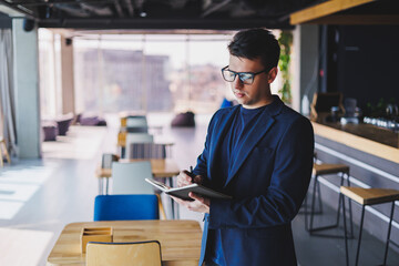 Young freelancer man working in a cafe with a notepad, a businessman with a notepad, a man in a jacket and glasses