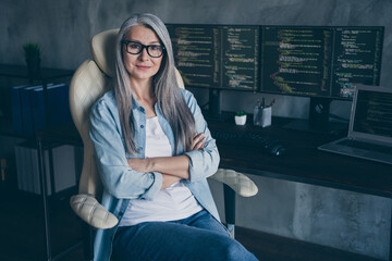 Portrait of aged successful lady sitting chair crossed arms look camera web design workplace indoors