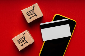 Smartphone, boxes and credit card on red background close-up. Online shopping concept