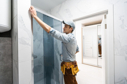 Workers Are Installing Glass Door Of The Shower Enclosure.