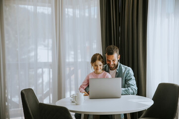 Father and daughter using laptop computer together