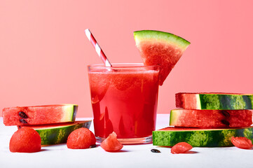 Close-up fresh watermelon juice or smoothie in glasses with watermelon pieces on pink background. Refreshing summer drink