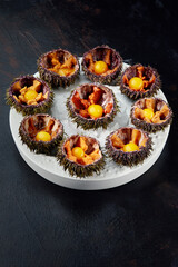 Sea urchins in a ceramic bowl with ice on. Sea urchin dish with quail egg and soy sauce.
