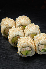 Traditional delicious fresh sushi roll set on a black background. Sushi roll with rice, cream cheese, avocado, salmon, sesame. Philadelphia. Sushi menu. Japanese kitchen, restaurant.