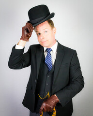 Portrait of British Butler in Dark Suit and Leather Gloves Politely Tipping His Bowler Hat. Classic...