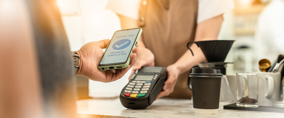 Fototapeta na wymiar Businessman using mobile payment technology to pay bill in coffee shop.man with manicure holding smartphone and using contactless payment system.new normal lifestyle concept