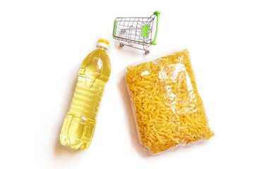Bottle of sunflower cooking oil, pasta packaging and shopping cart on a white background top view food photo. Grocery set image