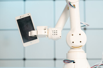 Phone in robot arm, bot concept on customer support hotline. Using artificial intelligence in a...