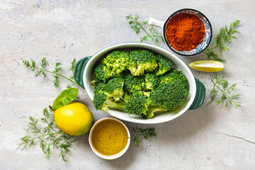 Set of raw ingredients for preparing a healthy vegetarian dinner. Baked broccoli with spices and green beans on a light stone background
