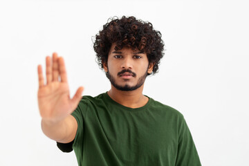 Portrait of young Asian man showing stop gesture and looking at camera on a white background