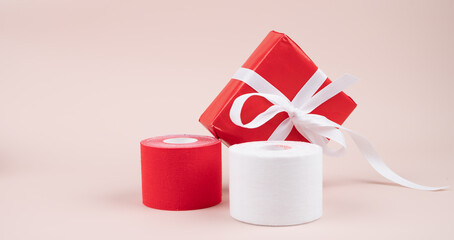 Lifting or kinesio tape rolls and gift box on pink background with copy space. Alternative medicine concept