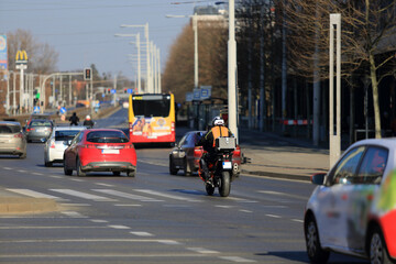 Motocyklista z bagarznikiem jedzie ulicą Wrocławia. - obrazy, fototapety, plakaty